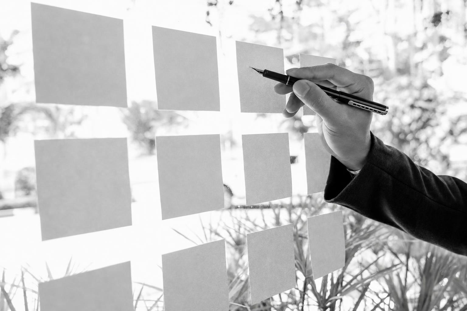 Hands placing sticky notes on a glass wall while planning an MVP launch